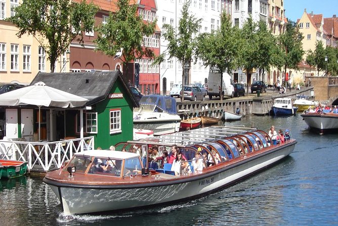 A guided canal boat passing painted gable houses in central Copenhagen